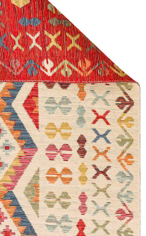 Load image 1 in gallery view. The Soft Mosaic - Washable Reversible Kilim - NMD08 features a cream background with multicolored geometric motifs, a bordered design, and a red underside decorated with diamond and cross shapes. Rug shown with one corner folded over.