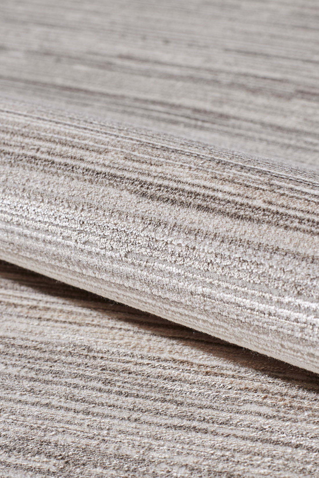 A close-up of the Soft Stripe Serenade Modern Rug - EW2814 highlights its machine-made quality, soft woven texture, and stylish light beige and grey horizontal stripes for a modern, elegant look in neutral tones.