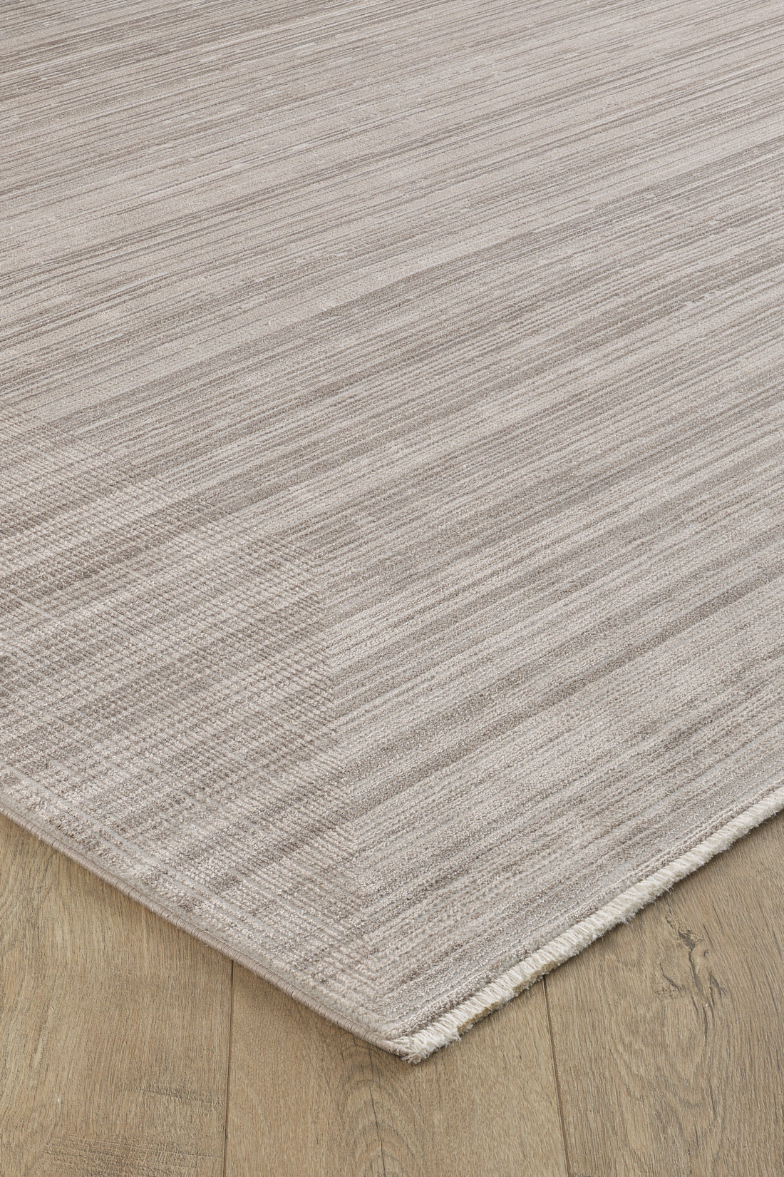 A close-up of the Soft Stripe Serenade Modern Rug - EW2814 in light beige with subtle horizontal stripes on a wooden floor, showcasing its soft, machine-made texture and neutral tones.