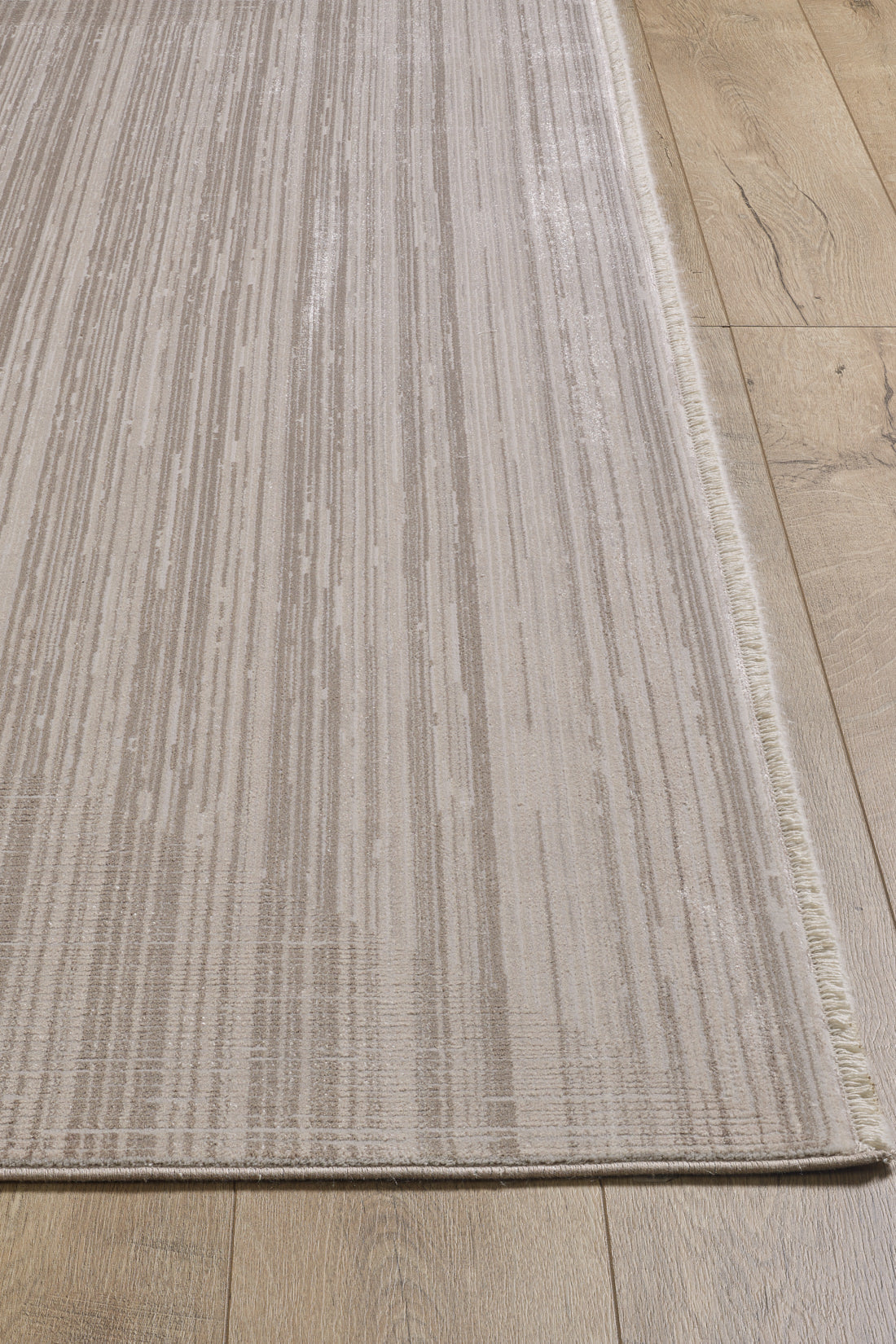 The Soft Stripe Serenade Modern Rug - EW2814, featuring beige and light brown vertical stripes and fringe on one edge, adds modern style to a light wood floor.