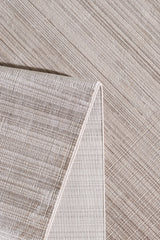 A close-up of the Soft Stripe Serenade Modern Rug - EW2814, featuring neutral tones and a subtle crisscross pattern. Partially folded at the corner, it showcases its textured surface and refined edge detailing for a modern look.