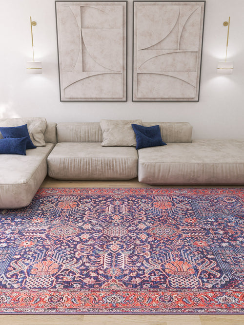 Bild 1 in Galerieansicht laden. A modern living room with a beige sectional sofa, blue pillows, abstract wall art, and the Solstice Red Navy Washable Rug (LCC3026) in a custom size—its red and blue patterns are ideal for high-traffic wooden floors.