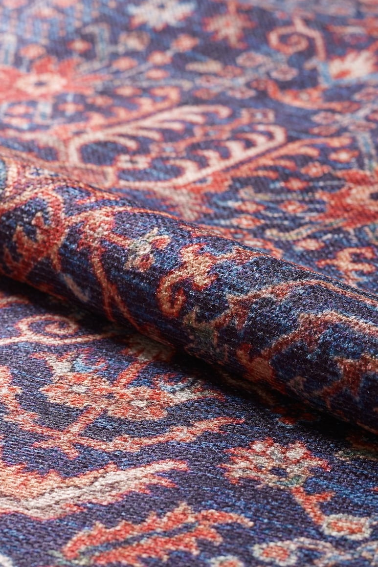 A close-up of the Solstice Red Navy Washable Rug - LCC3026 (Custom Size), showcasing ornate blue, red, and cream patterns. Its detailed weaving and vibrant colors make this washable rug perfect for high-traffic areas.
