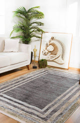 A modern living room featuring the Sophisticated Trellis - Washable Rug - JR1194 (Custom Size) in gray, perfect for high-traffic areas, paired with a white sofa, accent pillow, tall green plant, gold trophy decor, small cactus, and framed horse artwork.