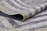 A close-up of the Sophisticated Trellis - Washable Rug - JR1194 (Custom Size) shows its folded, textured surface, striped geometric pattern in gray, beige, and light yellow; lifted edge highlights its thickness and woven detail—perfect for high-traffic areas.