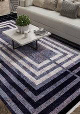 A modern living room features a white sofa, patterned cushions, a marble coffee table with a plant and cups, all atop the Sophisticated and Chic - Washable Rug - JR1409 in blue, gray, and white geometric patterns.