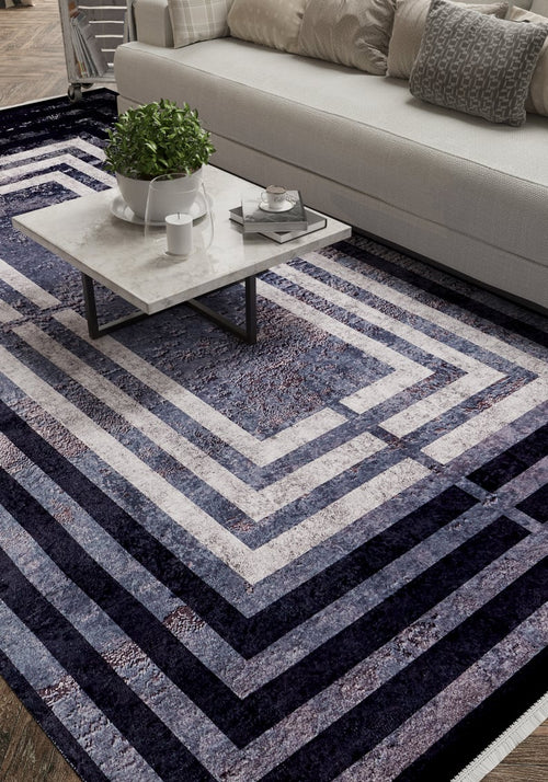 Load image 1 in gallery view. A modern living room features a white sofa, patterned cushions, a marble coffee table with a plant and cups, all atop the Sophisticated and Chic - Washable Rug - JR1409 in blue, gray, and white geometric patterns.