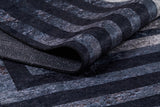 A close-up of the Sophisticated and Chic - Washable Rug - JR1409 (Custom Size), featuring dark blue, gray, and black stripes with a partially folded underside—ideal for high-traffic spaces.