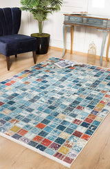 The Square Serenity - Washable Rug - JR1255 (Custom Size) features blue, red, orange, and yellow squares that brighten wooden floors. Ideal for high-traffic areas, it pairs beautifully with a blue chair, desk, plant, birdcage, and magazine.