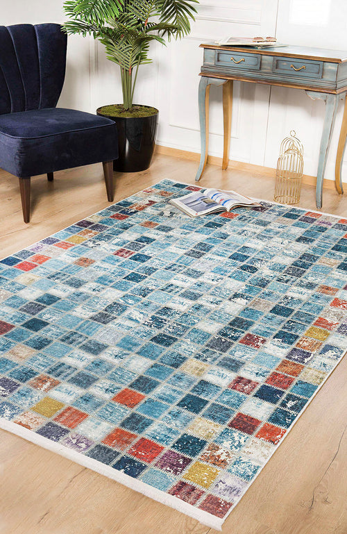 Load image 1 in gallery view. The Square Serenity - Washable Rug - JR1255 (Custom Size) features blue, red, orange, and yellow squares that brighten wooden floors. Ideal for high-traffic areas, it pairs beautifully with a blue chair, desk, plant, birdcage, and magazine.