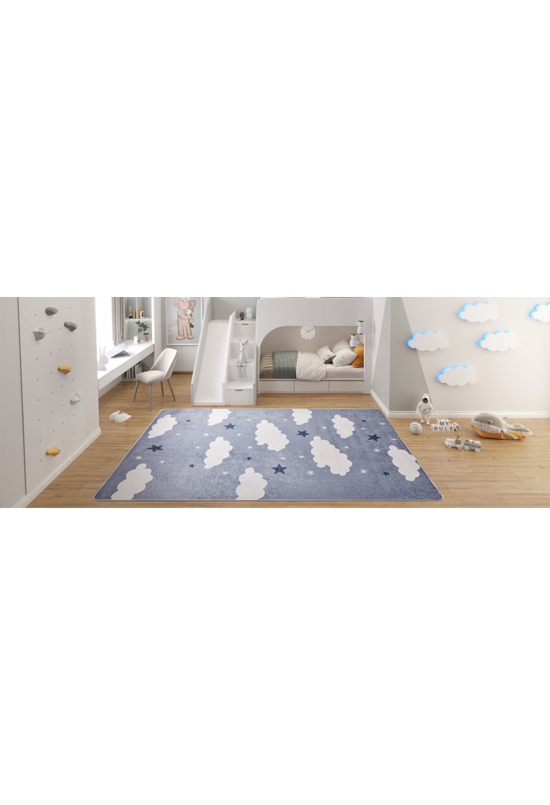 A children’s bedroom featuring the Starry Cloudscape - Machine-Washable Rug JRC045 with blue, white clouds and stars, paired with a bunk bed, climbing wall, desk and chair, stuffed toys, and cloud wall decor on light wood flooring.