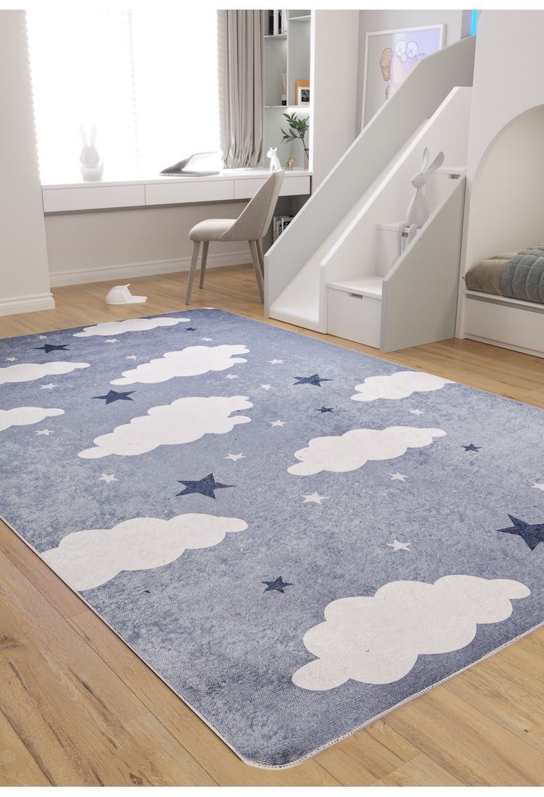 A bright, organized children’s playroom features the Starry Cloudscape - Machine-Washable Rug JRC045 (Custom Size) with blue, white clouds and stars, a slide with a toy bunny, wooden floors, and a desk by the window—easy to keep clean.