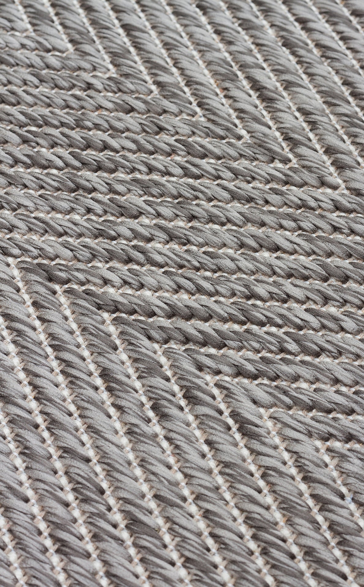 Close-up of Storm Weave - Kilim - MNO02, a flatwoven polyester fabric with a grey and white chevron pattern, featuring tightly interlaced threads that form a textured, diagonal design perfect for modern minimalism.