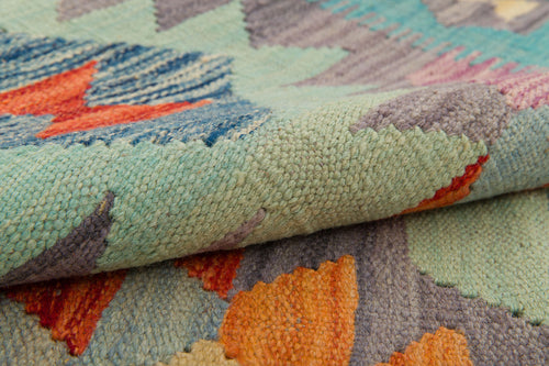 Load image 1 in gallery view. A close-up of the Striped Elegance - Handwoven Kilim, showcasing its vibrant blue, orange, green, and purple geometric patterns. The rug’s flatweave texture and detailed craftsmanship are clearly visible.