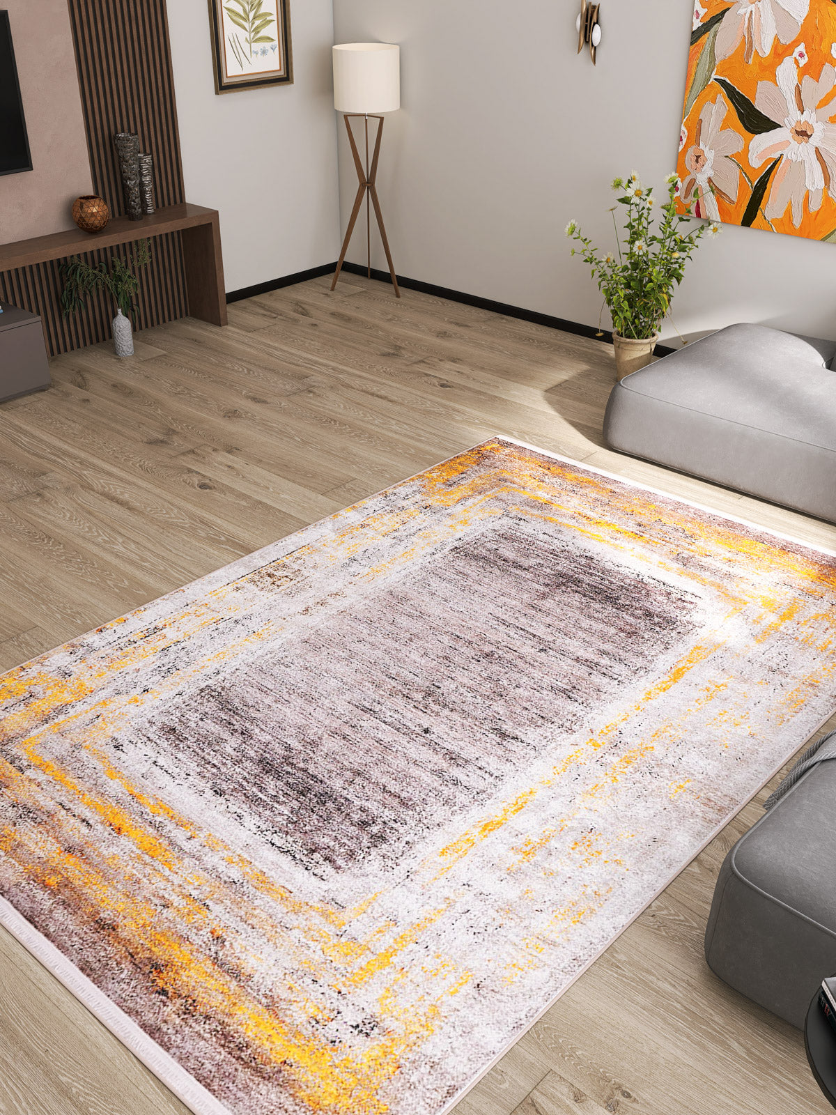 A modern living room with light wood floors, the Subtle Elegance - Washable Rug - JR1174 in gray with yellow and brown accents—perfect for high-traffic areas—gray sofas, a floor lamp, floral wall art, and a shelf with plants and decor.