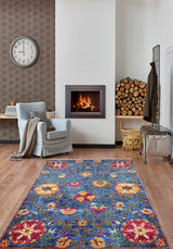 A cozy living room with the Summer Bouquet - Washable Rug - JR1358 (Custom Size), perfect for high-traffic areas, a light blue armchair with a blanket, modern fireplace, large wall clock, and wooden floors.
