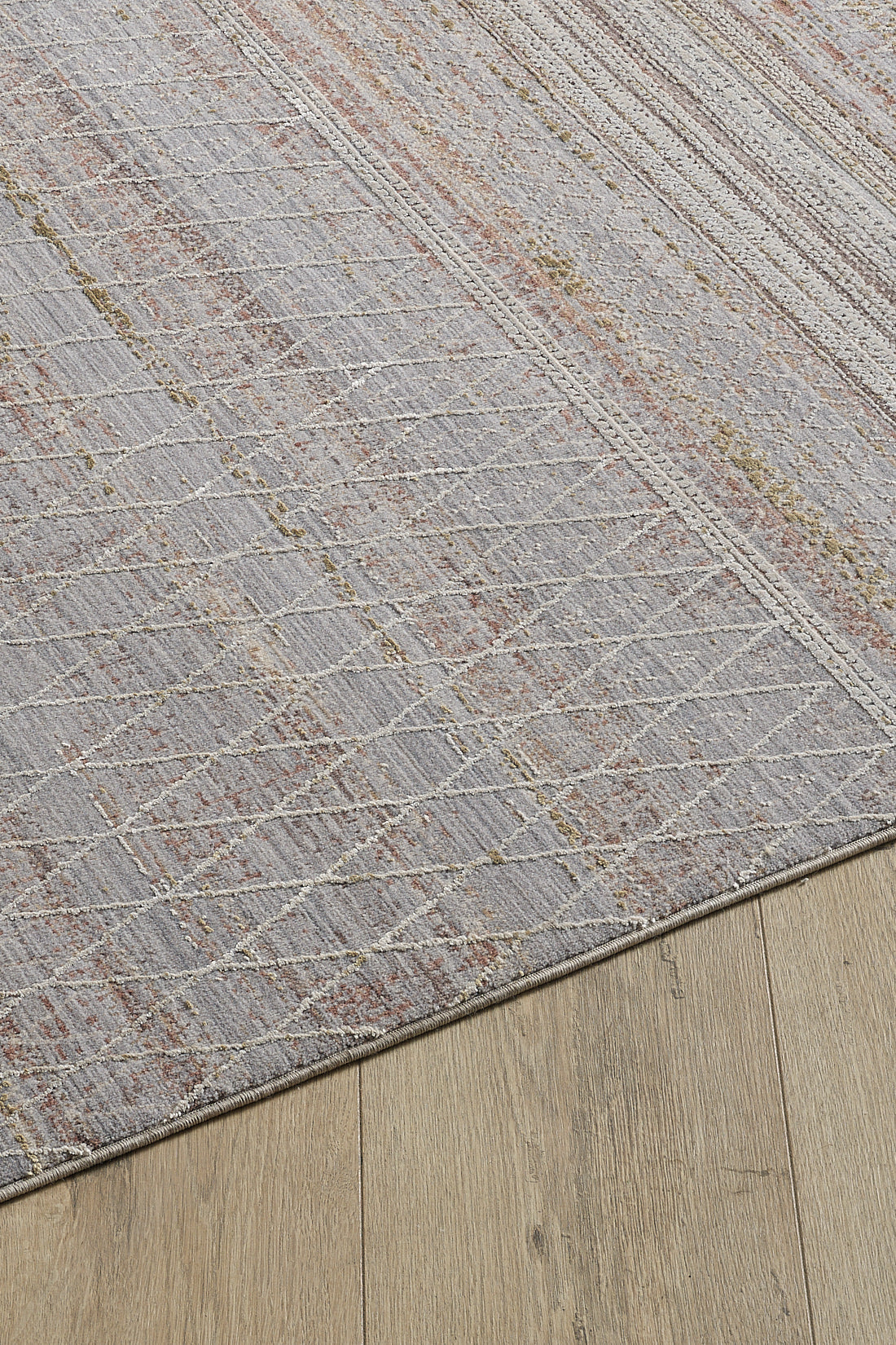 A close-up of the Sunkissed Boho Trellis Rug - M627M, featuring subtle white geometric lines and muted red accents, displayed on a light wooden floor.