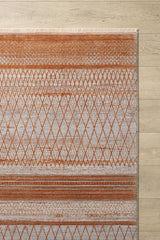 The Tangerine Dream Trellis Rug - HRD008 is a modern diamond pattern rug with orange and beige geometric designs, horizontal lines, and fringed edges on one side, placed on a light wood floor. This rug is machine-made for added durability.