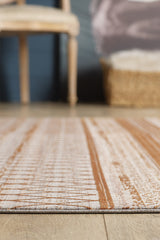 A close-up of the Tangerine Dream Trellis Rug - HRD008 in beige and rust on a wooden floor. A wicker basket and light wood chair are visible in the blurred background, set against a dark wall.