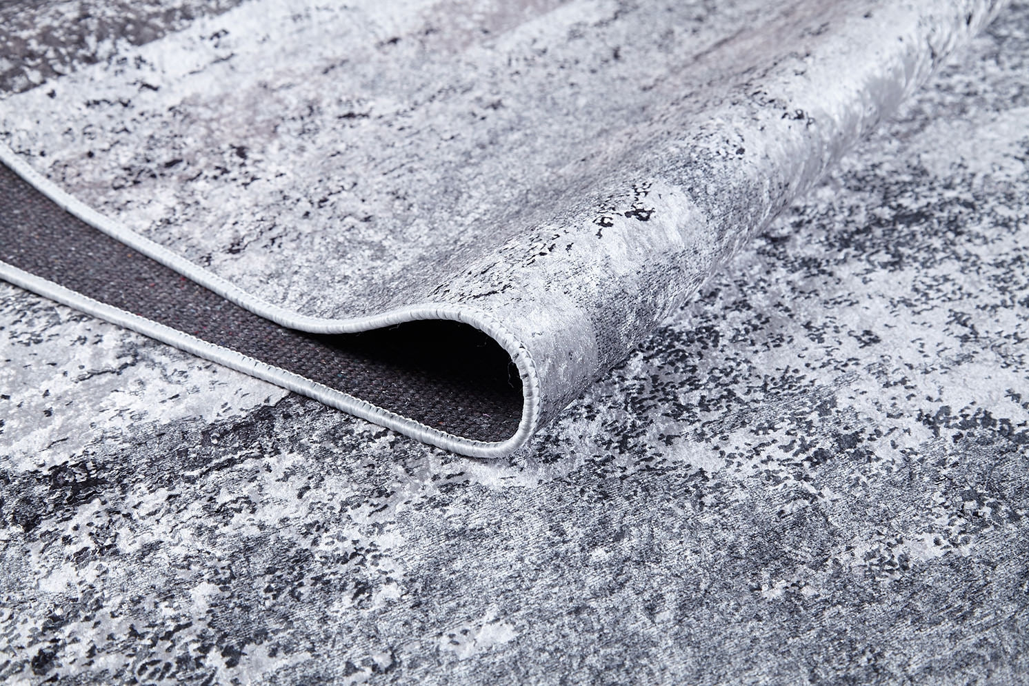 A close-up of the Techno Flux - Washable Rug - JR1814 (Custom Size) in gray-anthracite shows its modern abstract pattern, thin edge trim, and dark non-slip backing—perfect for high-traffic areas.