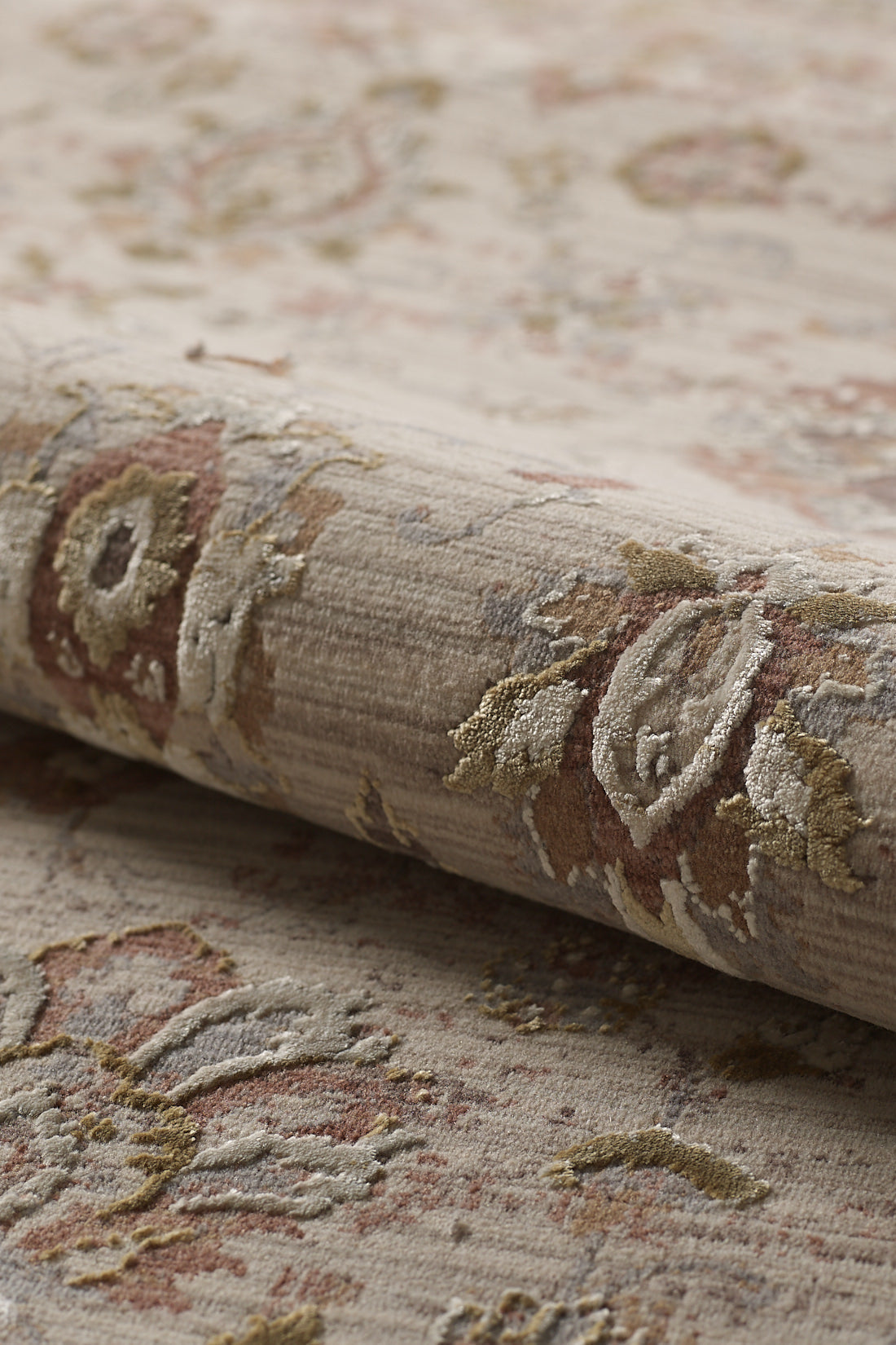 A close-up of the Timeless Petals Oushak Rug - Sand (M621N), showcasing its subtle floral pattern in muted brown, gold, and red tones with textured fibers and a soft, vintage look.