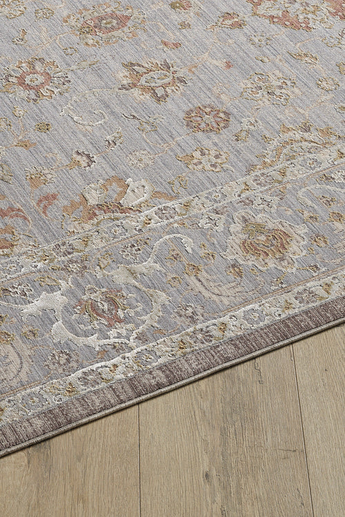 Bild 1 in Galerieansicht laden. A close-up of the Timeless Petals Oushak Rug - Silver - M621O, featuring a floral and vine pattern in muted pastels with a beige border, placed on a light wood floor.