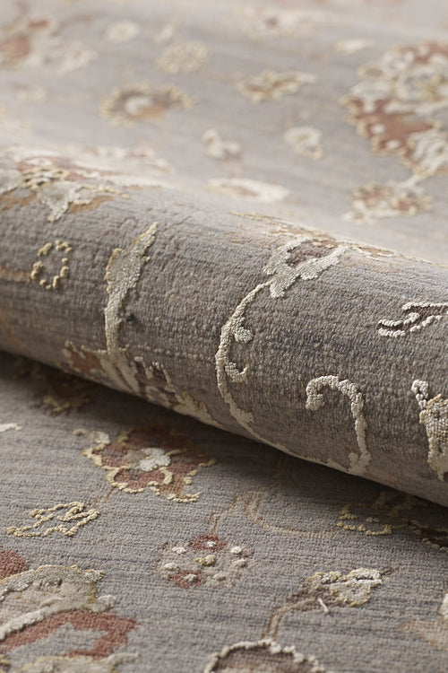 Bild 1 in Galerieansicht laden. A close-up of the Timeless Petals Oushak Rug - Silver (M621O) shows its textured beige and light brown pattern on a muted gray background, with a soft surface and slightly raised areas for added depth.