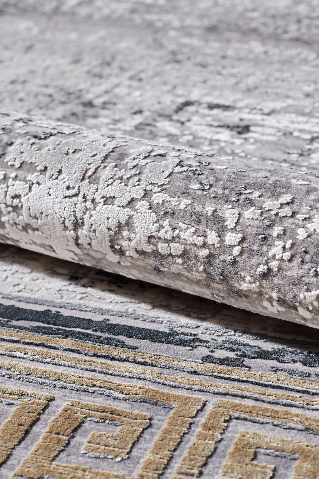 A close-up of the Timeless Remix Bordered Rug - Beige - MT187, a machine-made rug with abstract grey and white patterns and a yellow and grey Greek key border.