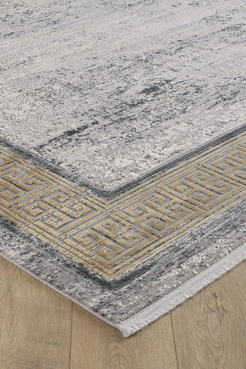 Load image 1 in gallery view. A close-up of the Timeless Remix Bordered Rug - Beige - MT187, a machine-made rug with a distressed gray pattern, gold and gray Greek key border, and short white fringe, seen on a light wooden floor.