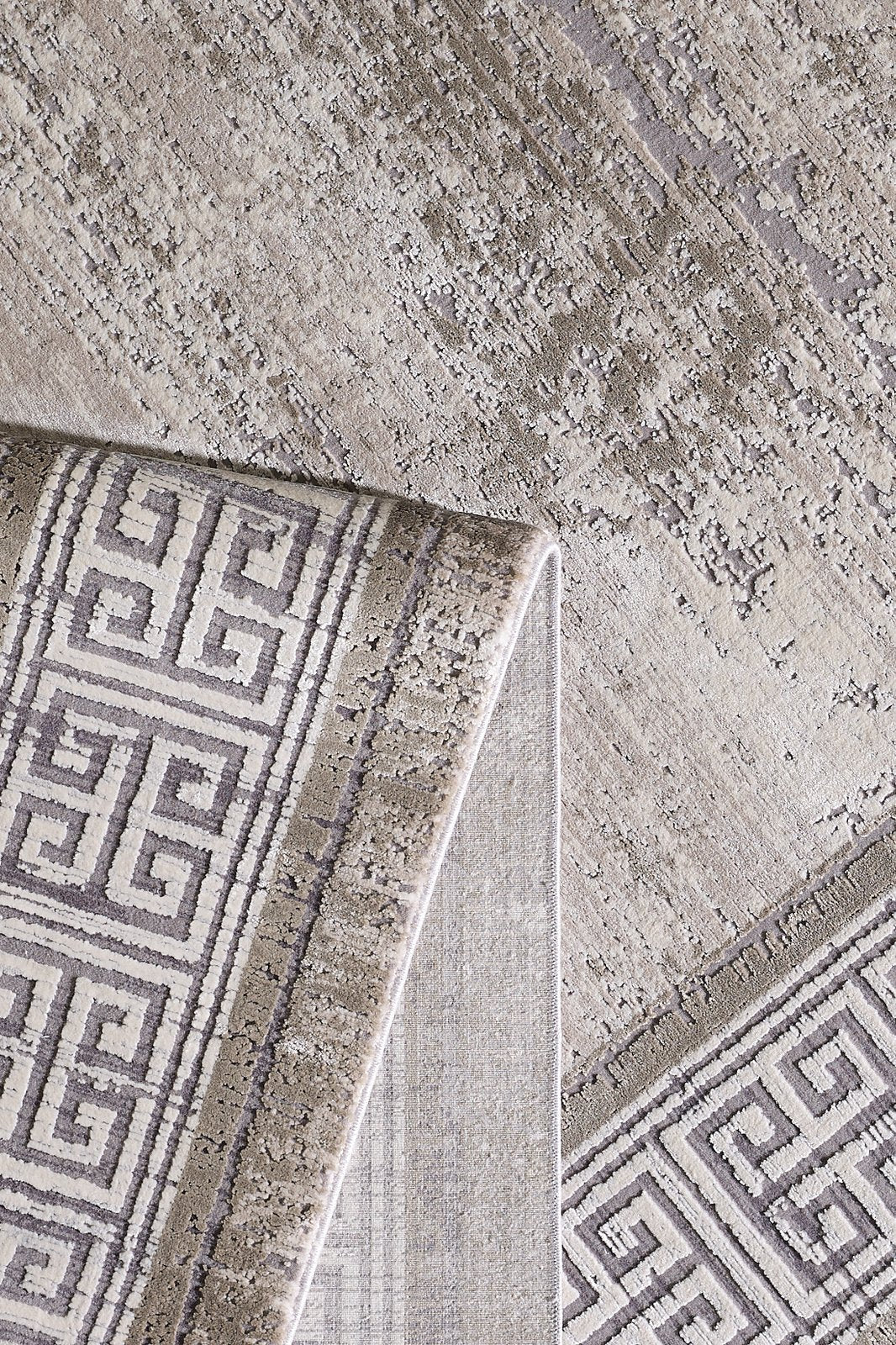 A close-up of the Timeless Remix Bordered Rug - Cream - MT189 shows a folded corner revealing its geometric Greek key design and textured, high-quality acrylic-viscose surface on both sides.