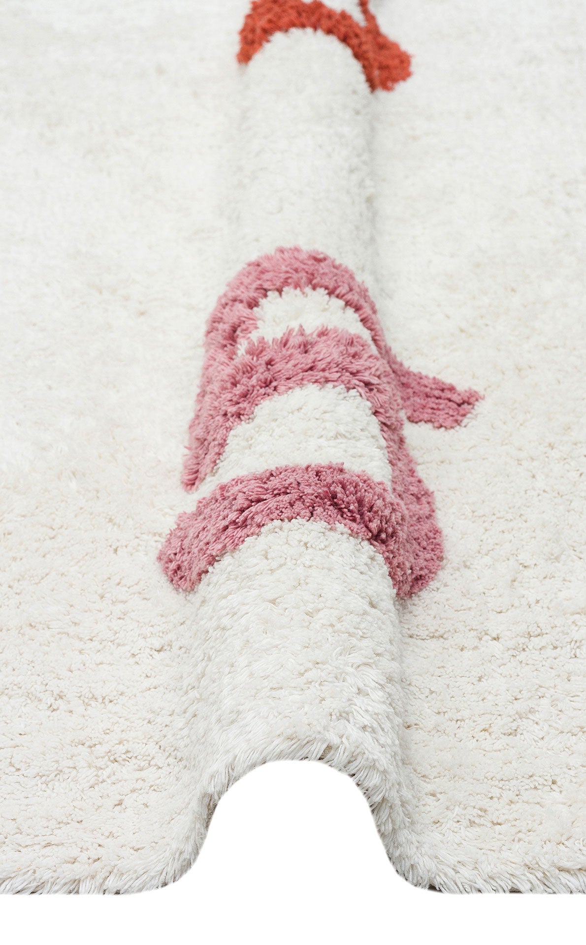 A close-up of the Tiny Joy - Washable Shaggy - CBN02 rug shows a thick, white shag with raised wavy pink and red patterns, partially folded to highlight its soft texture—an ideal playful accent for any kid’s room.