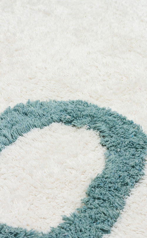 Load image 1 in gallery view. Close-up of the Tiny Joy - Washable Shaggy - CBN02, a fluffy white rug with a textured teal oval pattern. Its soft, plush surface is perfect for adding comfort and style to any kids room rug collection.