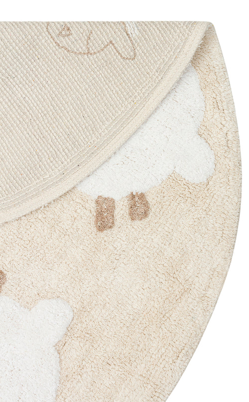 Load image 1 in gallery view. A close-up of the Tiny Motion - Washable Shaggy - CBN11 round beige and white cotton rug featuring a sheep design, partially folded to display both the playful front pattern and its textured backing.