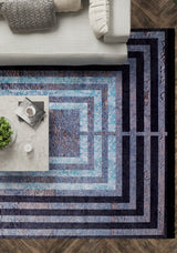 A top-down view of a living room with a gray couch, marble coffee table, and the Traditional and Timeless - Washable Rug - JR1408 in black and blue—perfect for high-traffic areas—on a wooden floor.