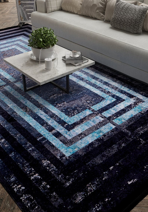 Load image 1 in gallery view. A modern living room with a white sofa, gray and white cushions, a marble coffee table, and the Traditional and Timeless - Washable Rug - JR1408—a blue geometric rug perfect for high-traffic areas. A potted plant and tray with cups rest on the table.
