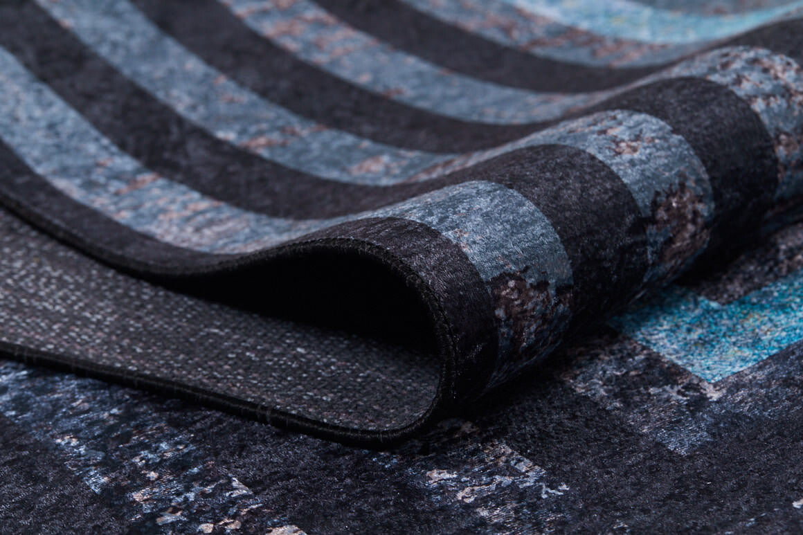 A close-up of the Traditional and Timeless - Washable Rug - JR1408 (Custom Size), partially folded to show its textured surface with blue, gray, and black stripes and sturdy backing—perfect for high-traffic areas.