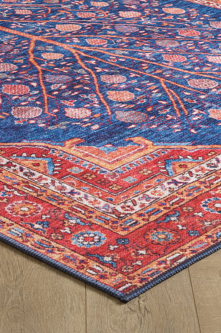 The Tree of Plenty Red Blue Washable Rug - LCC3031 boasts intricate blue, red, orange, and pink floral and geometric patterns, making it ideal for high-traffic areas. Shown on a light wood floor.