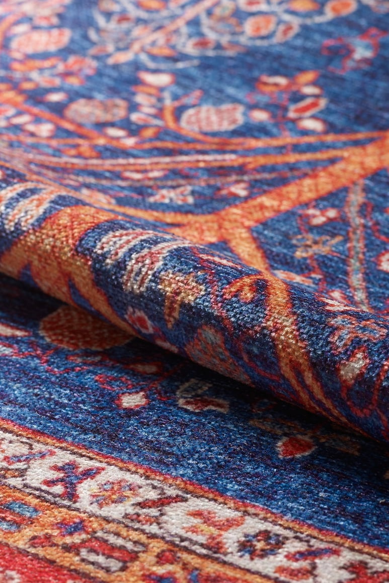 A close-up of the Tree of Plenty Red Blue Washable Rug (LCC3031, Custom Size) showcases its vibrant floral and geometric patterns in blue, orange, and red—perfect for high-traffic spaces and easy to clean.