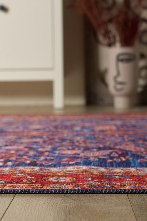 Bild 1 in Galerieansicht laden. A close-up of the Tree of Plenty Red Blue Washable Rug - LCC3031 (Custom Size) on a wooden floor, with a white cabinet and an abstract face vase in the background—ideal for allergy-sensitive or high-traffic homes.