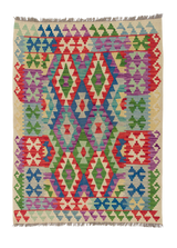 The Tribal Essence - Handwoven Kilim is a colorful flatweave rug with geometric diamond patterns in red, green, blue, purple, and cream. Symmetrical designs and short edge fringe add to its charm.