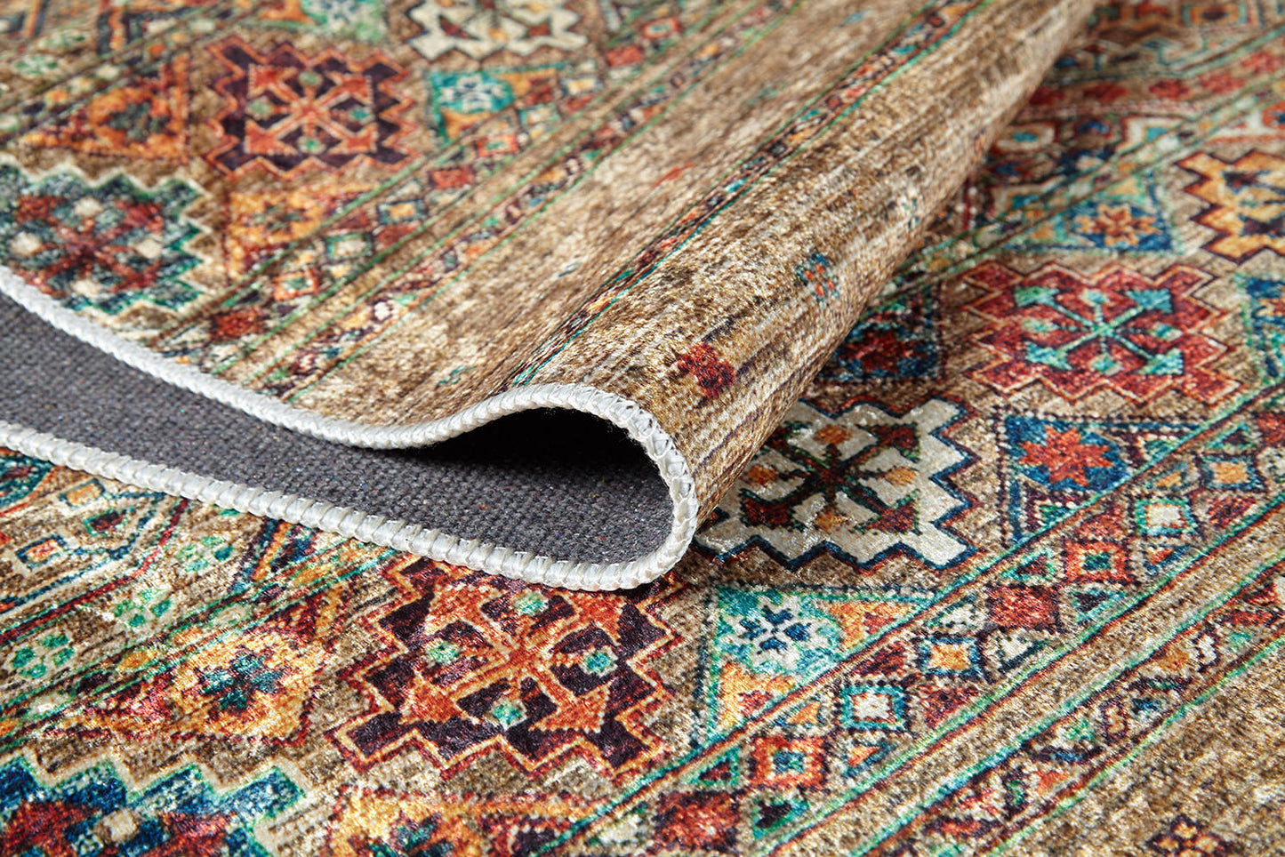 A close-up of the Tribal Tango - Washable Rug - JR5089 (Custom Size) shows its vibrant red, blue, orange, and cream geometric patterns. A folded corner reveals sturdy stitching and underside—perfect for high-traffic areas and easy cleaning.