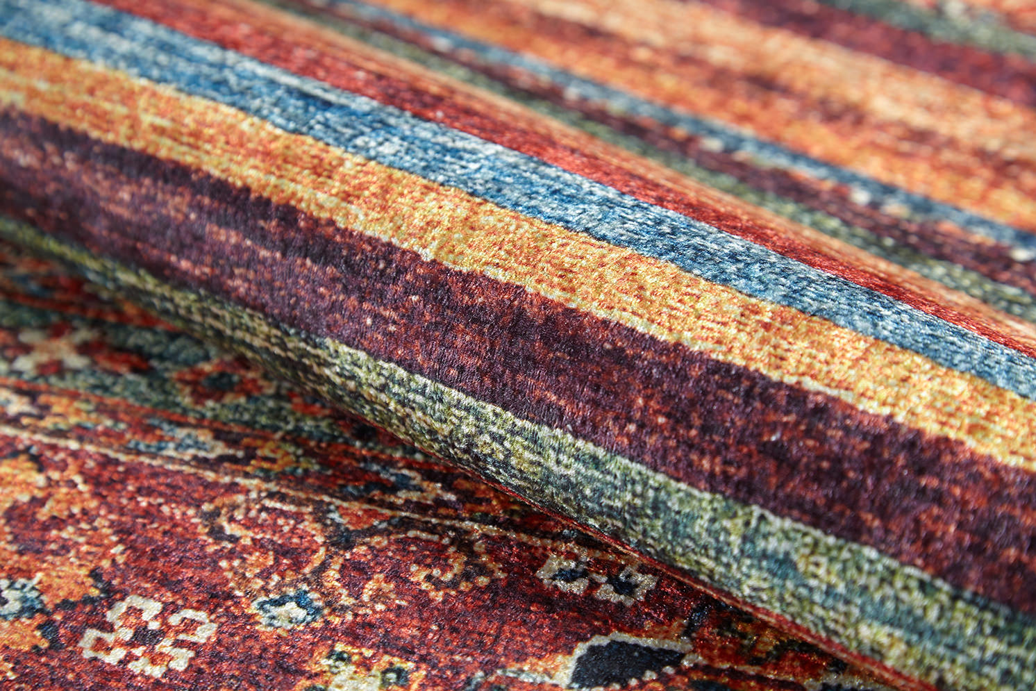 A close-up of the Tropic Thunder - Washable Rug - JR5077 (Custom Size) reveals multicolor horizontal stripes in red, yellow, and blue with detailed floral and geometric patterns in the background.