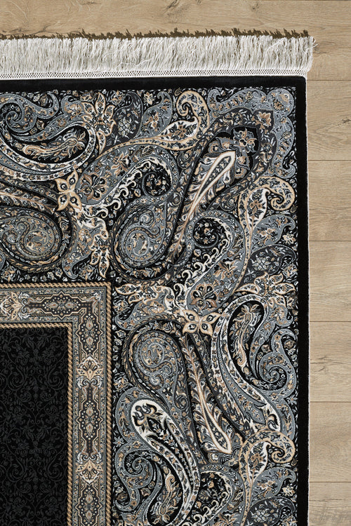 Load image 1 in gallery view. A detailed section of the Turkish Mirage Silk Medallion Rug - Obisidan - 1168D shows intricate floral and paisley patterns with a paisley border in black, gray, and beige on a light wooden floor, finished with white fringe.