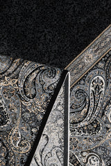 A close-up of the Turkish Mirage Silk Medallion Rug - Obsidian - 1168D showcases intricate paisley and floral patterns in black, gray, and beige, with a section folded to reveal its contrasting underside design.