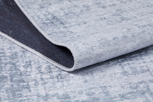 Bild 1 in Galerieansicht laden. A close-up of the Twilight Sky - Washable Rug - JR856 (Custom Size) in light gray-anthracite, showing a folded corner that reveals the dark underside—ideal for high-traffic areas and easily washable for convenience.