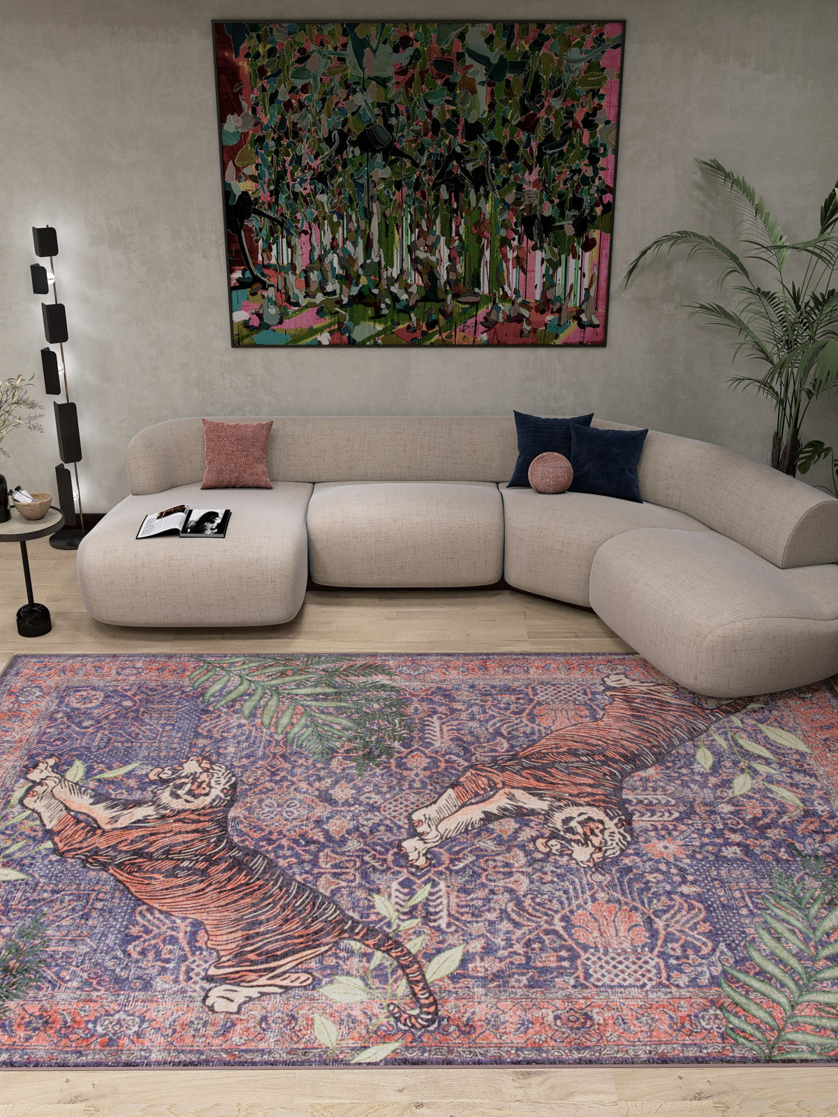 A modern living room featuring a curved beige sofa, colorful cushions, a floor lamp, leafy plant, vibrant abstract wall art, and the Stormstripe Echo - Washable Rug - JR0046 with blue tones, tigers, and floral patterns.