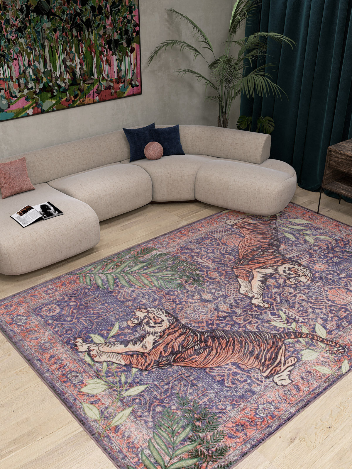 A modern living room with a curved beige sofa, colorful cushions, a low table with a magazine, dark green curtains, tall plant, vibrant abstract painting, and the Stormstripe Echo - Washable Rug - JR0046 featuring two tigers and leafy patterns.