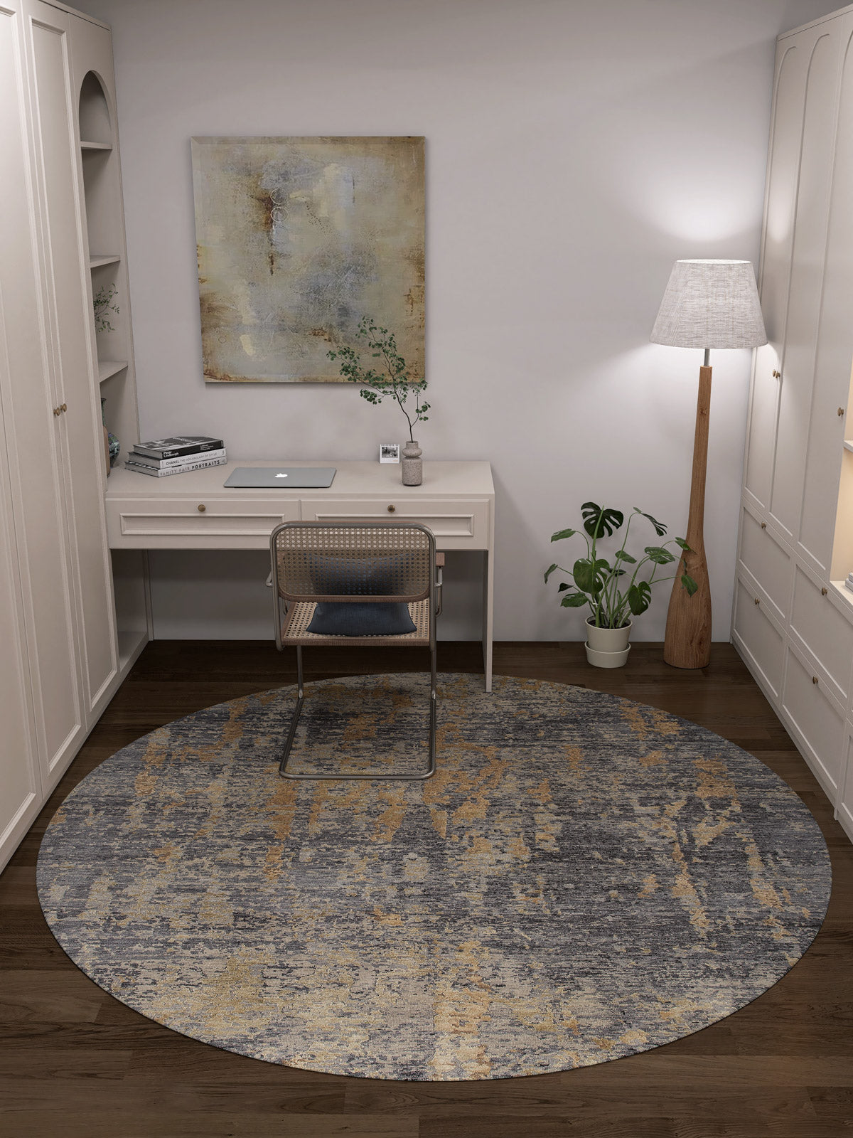 A minimalist home office with a white desk, laptop, chair, the Mystical Mosaic - Washable Rug - JRS003 (Custom Size) in gray and yellow for high-traffic areas, a floor lamp, potted plant, abstract artwork, white walls, and dark wooden floors.