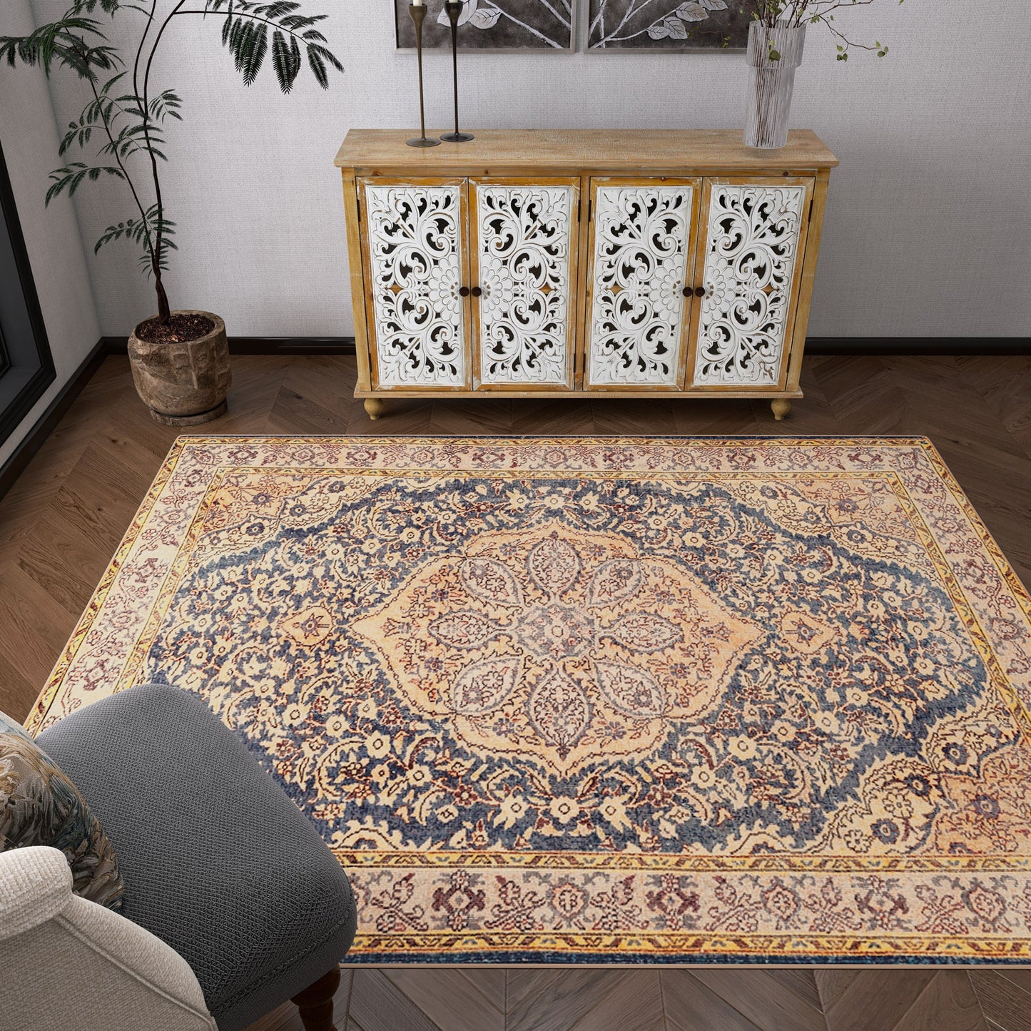 A living room with the Majestic Crest - Washable Rug - JRN1015 (Custom Size), a small wooden cabinet with white decorative doors, a potted plant, and a gray upholstered chair—ideal for traditional interiors.