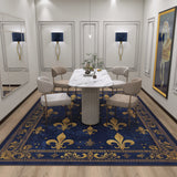 A modern dining room with a white marble table, four beige chairs, wall mirrors, framed art, two blue wall sconces, and the Midnight Fleur - Washable Rug - JRS017 in blue and gold—elegant decor with a classic touch.
